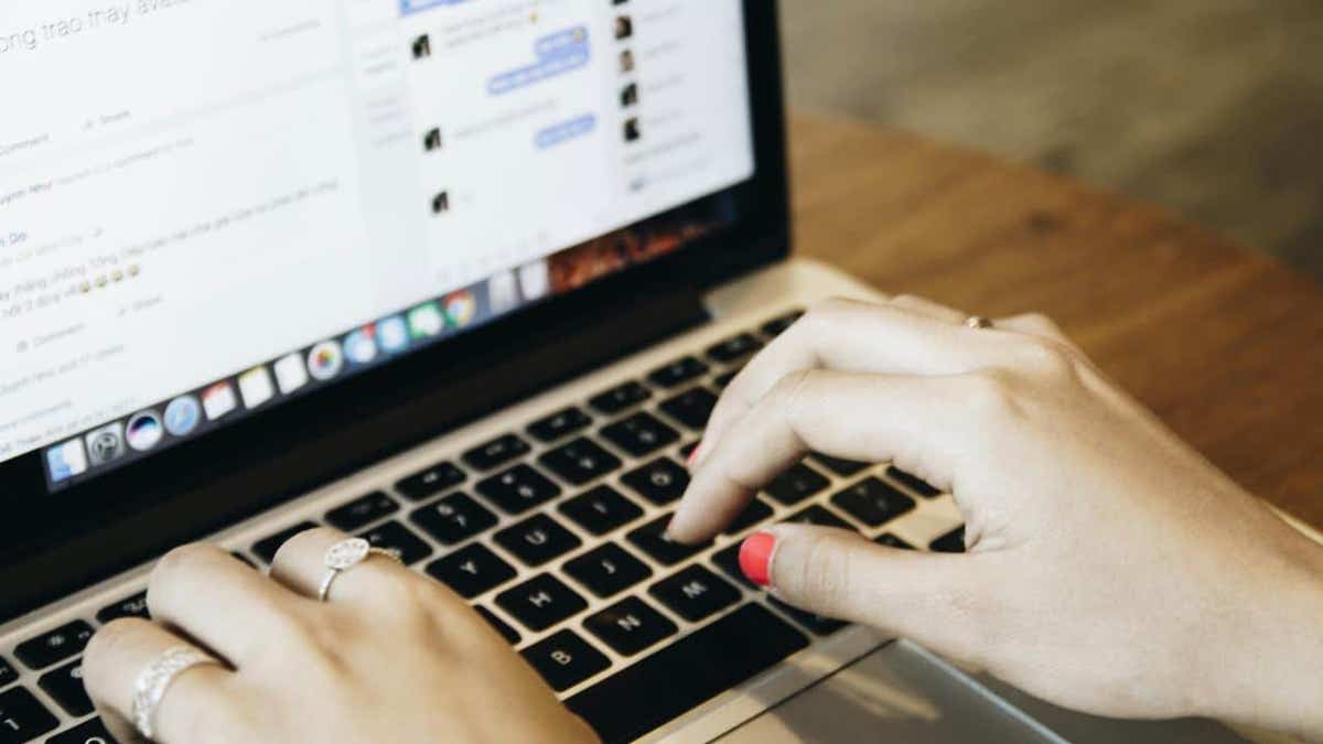 Woman typing on laptop with social media platform open.