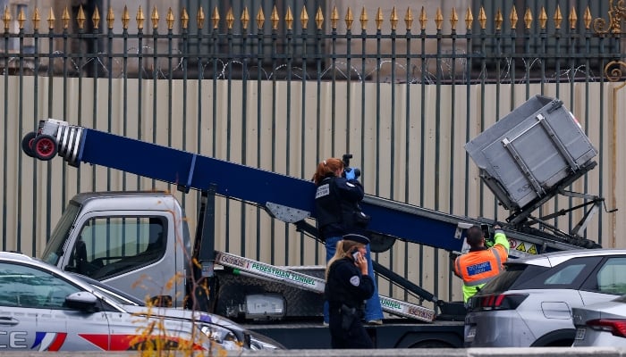 Police and forensic teams inspect a crane and a window believed to have been used in what the French Interior Ministry said was a robbery at the Louvre museum during which jewellery was stolen, as pedestrians pass nearby, in Paris, France, October 19, 2025. — Reuters