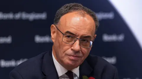 PA Media The Bank of England governor Andrew Bailey addresses a press conference wearing a dark suit and tie.