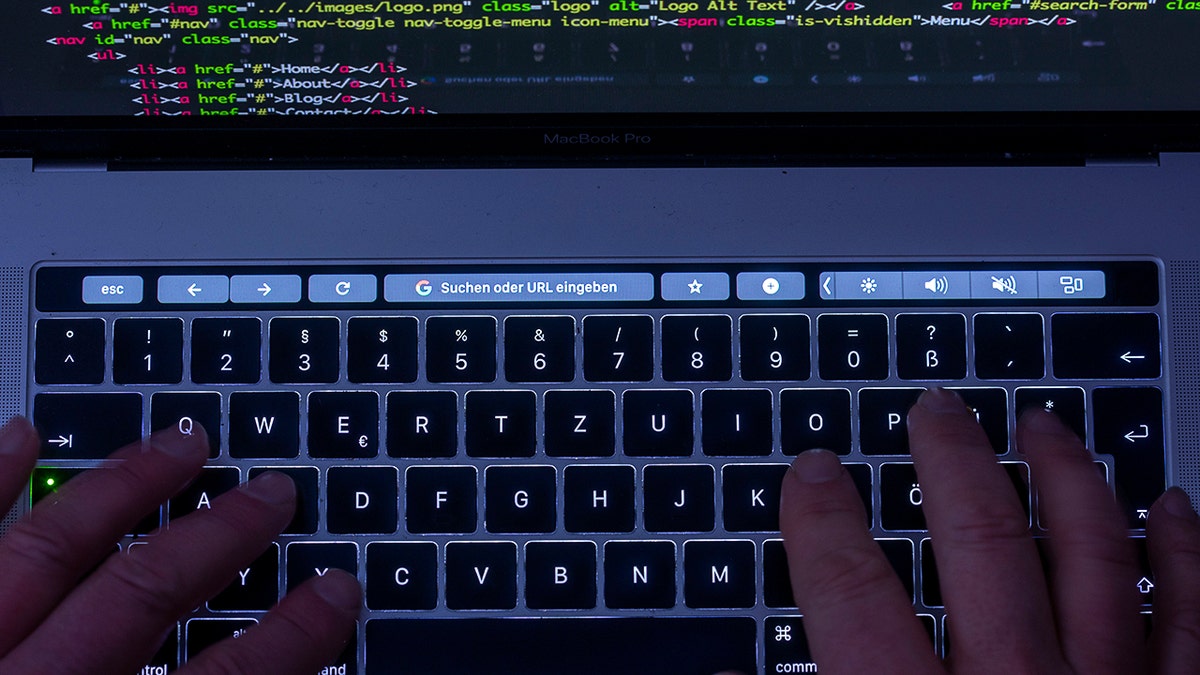 Hacker typing code on their laptop.